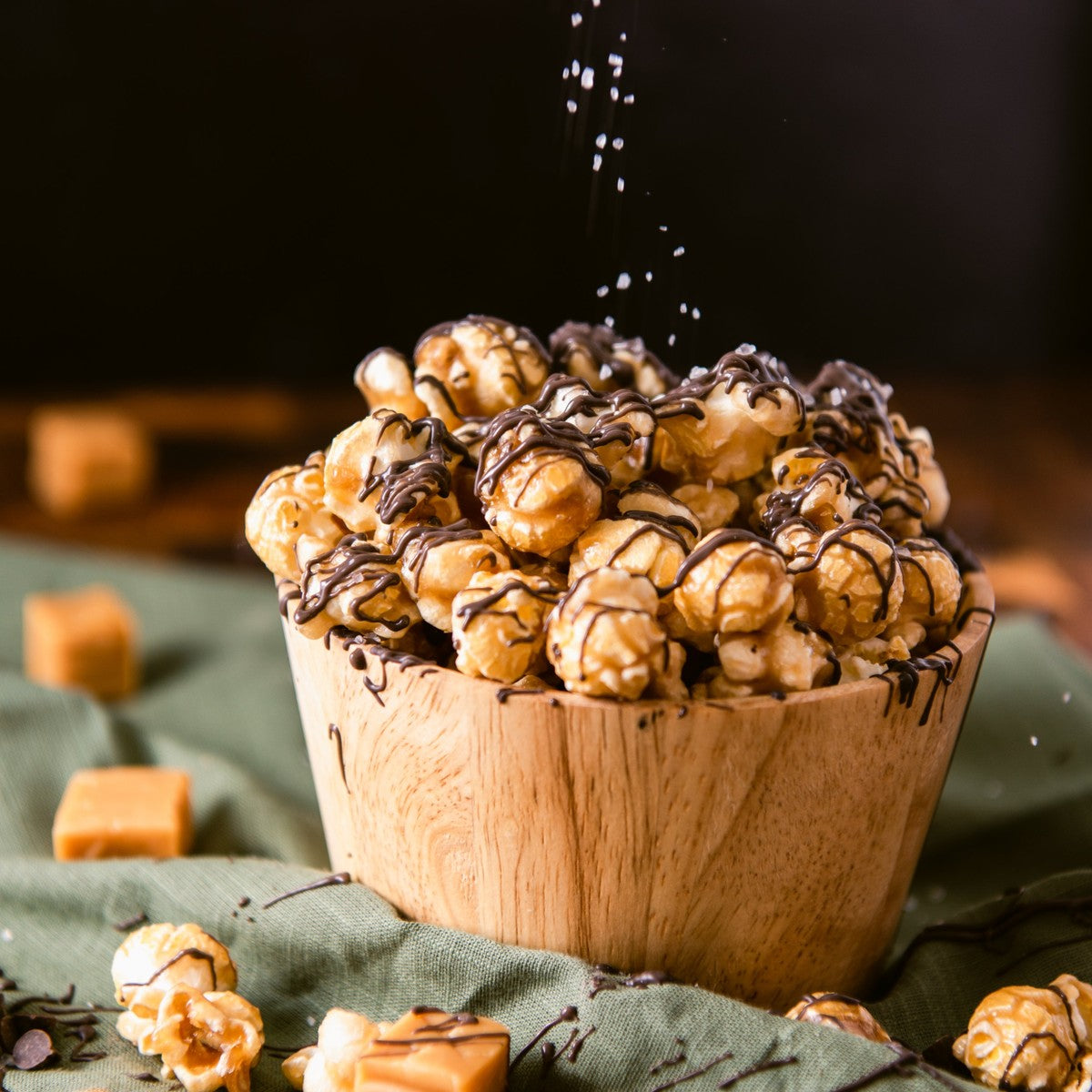 Caramel popcorn drizzled with dark chocolate and sea salt in a wooden bowl